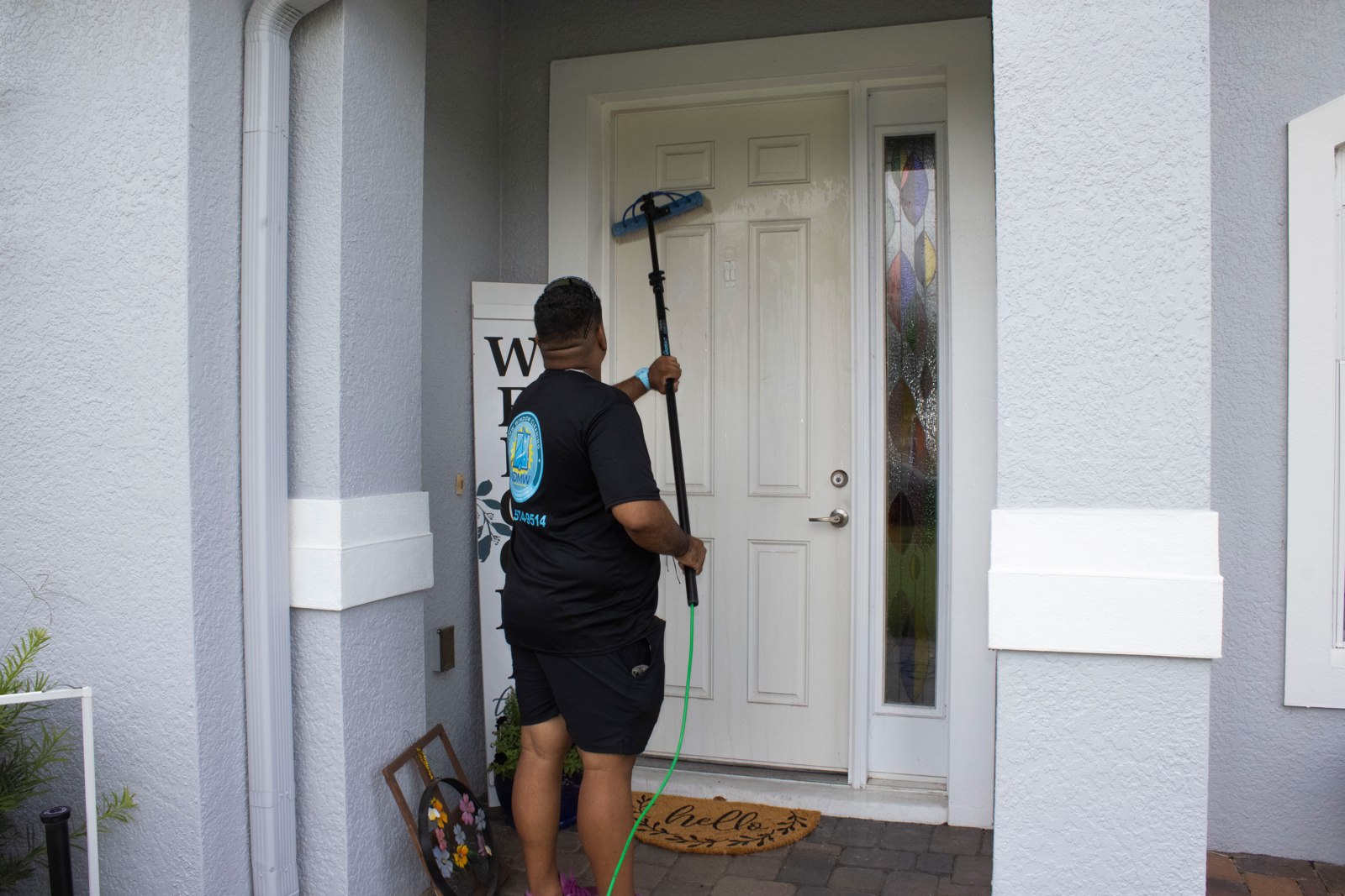 Glass Door Cleaning in Saint Cloud, FL: technician cleaning narrow glass beside a front door